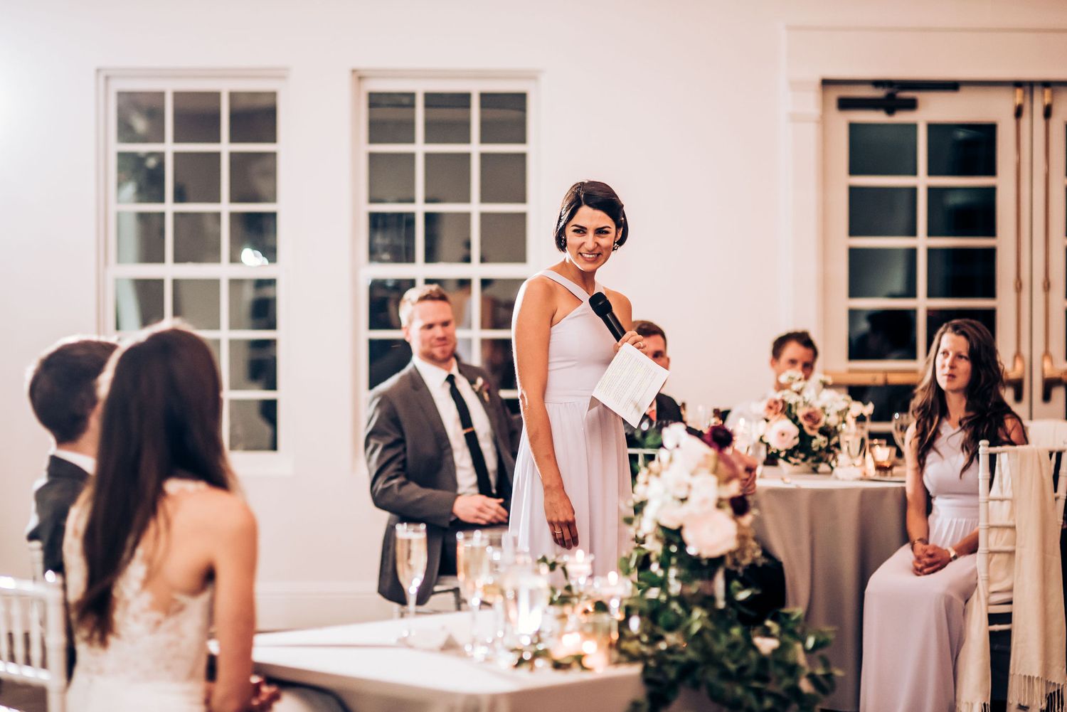 Wedding reception toast moment with elegant table settings and floral centerpieces.
