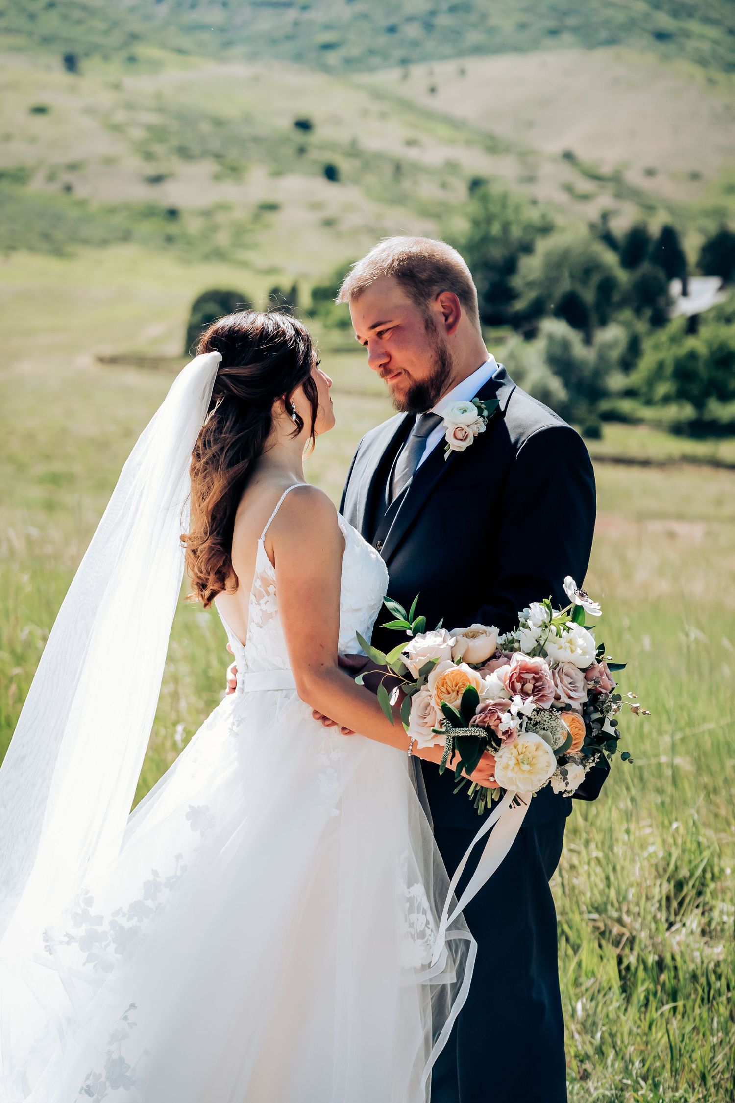 A couple shares an intimate moment in a scenic mountain meadow on their wedding day.