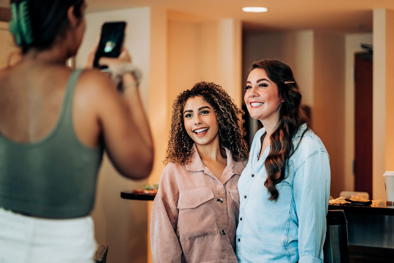 Three friends posing together for a photo in a bright indoor space.