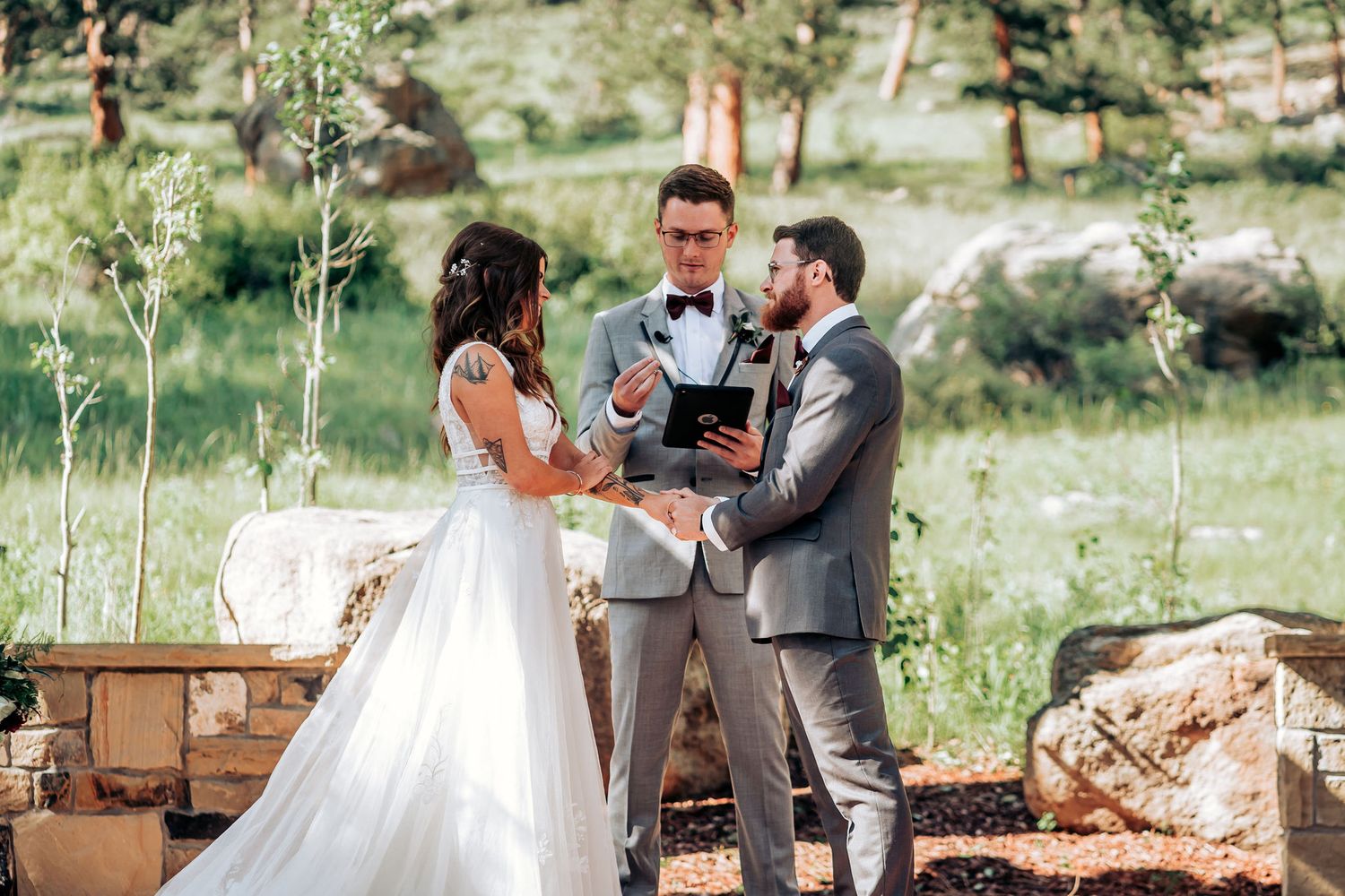 Intimate wedding ceremony moment under rustic wooden pergola in mountain landscape setting.