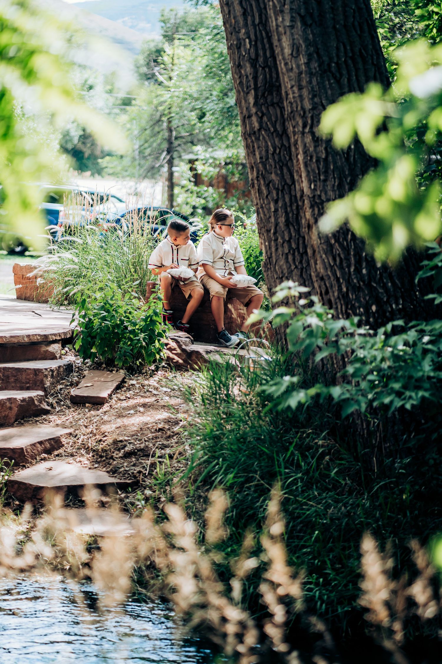 Two people sitting on stone steps near a creek in a serene forest setting.