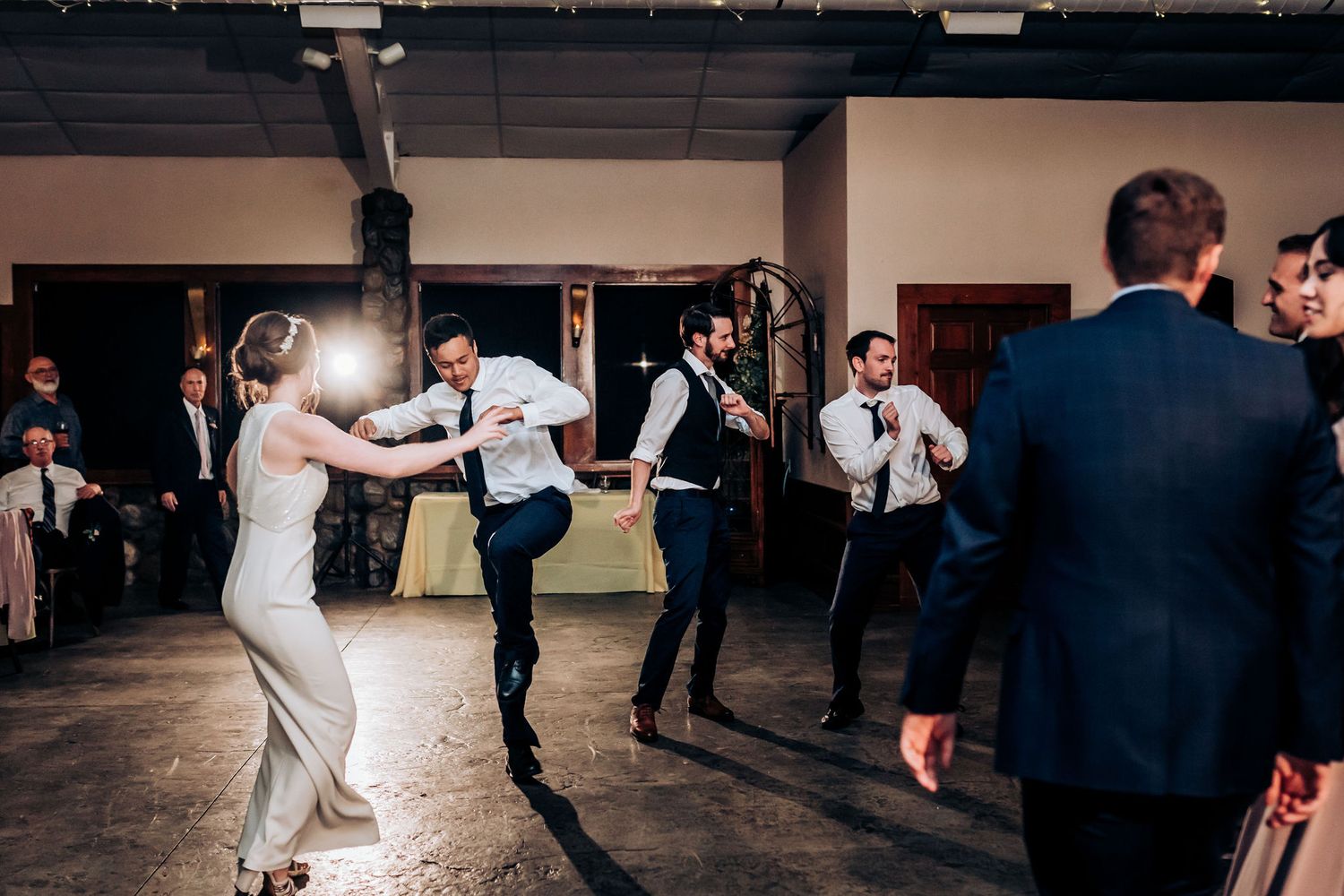 Wedding guests dancing and celebrating on an open dance floor at the reception.