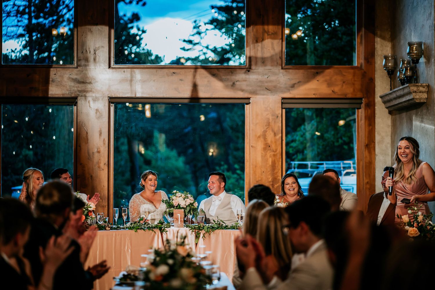 Wedding reception toast in rustic venue with large wooden beams and windows.