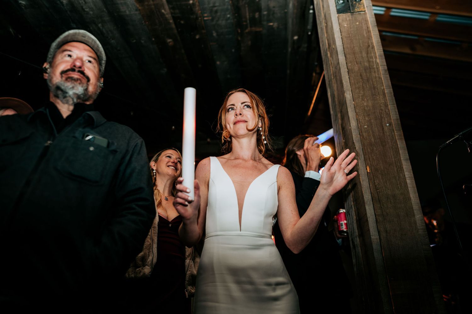 Wedding guests dancing and celebrating under dimly lit venue.