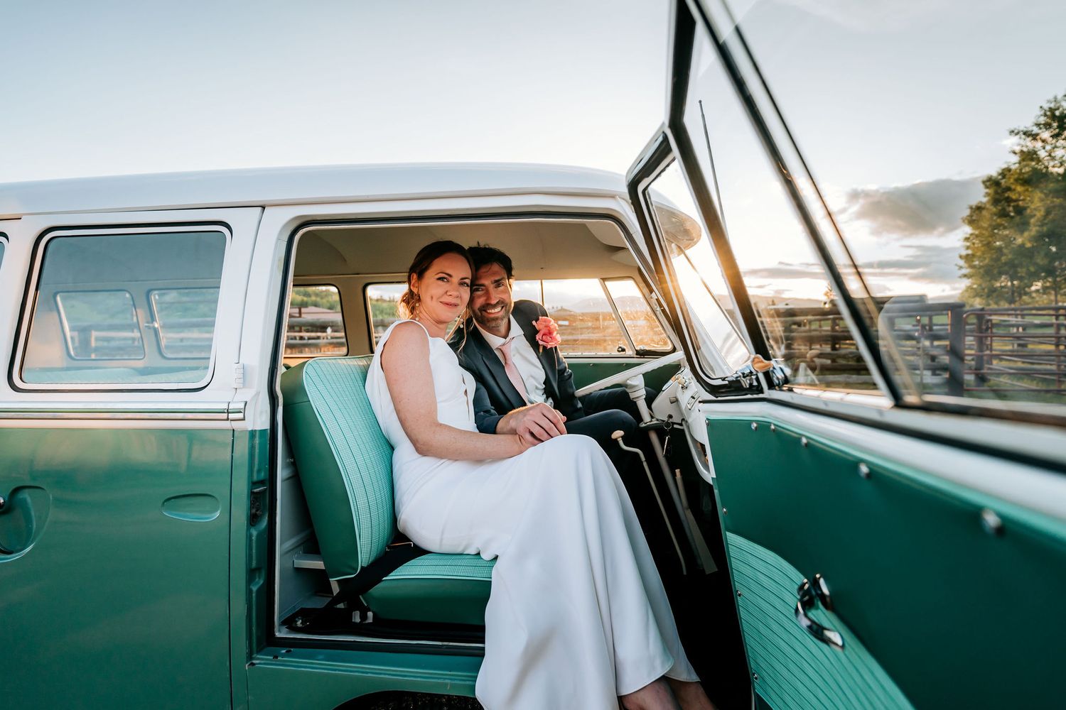 Inside view of couple in vintage Volkswagen van with turquoise interior during sunset.