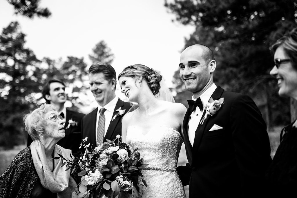Black and white wedding party photo with joyful expressions outdoors.