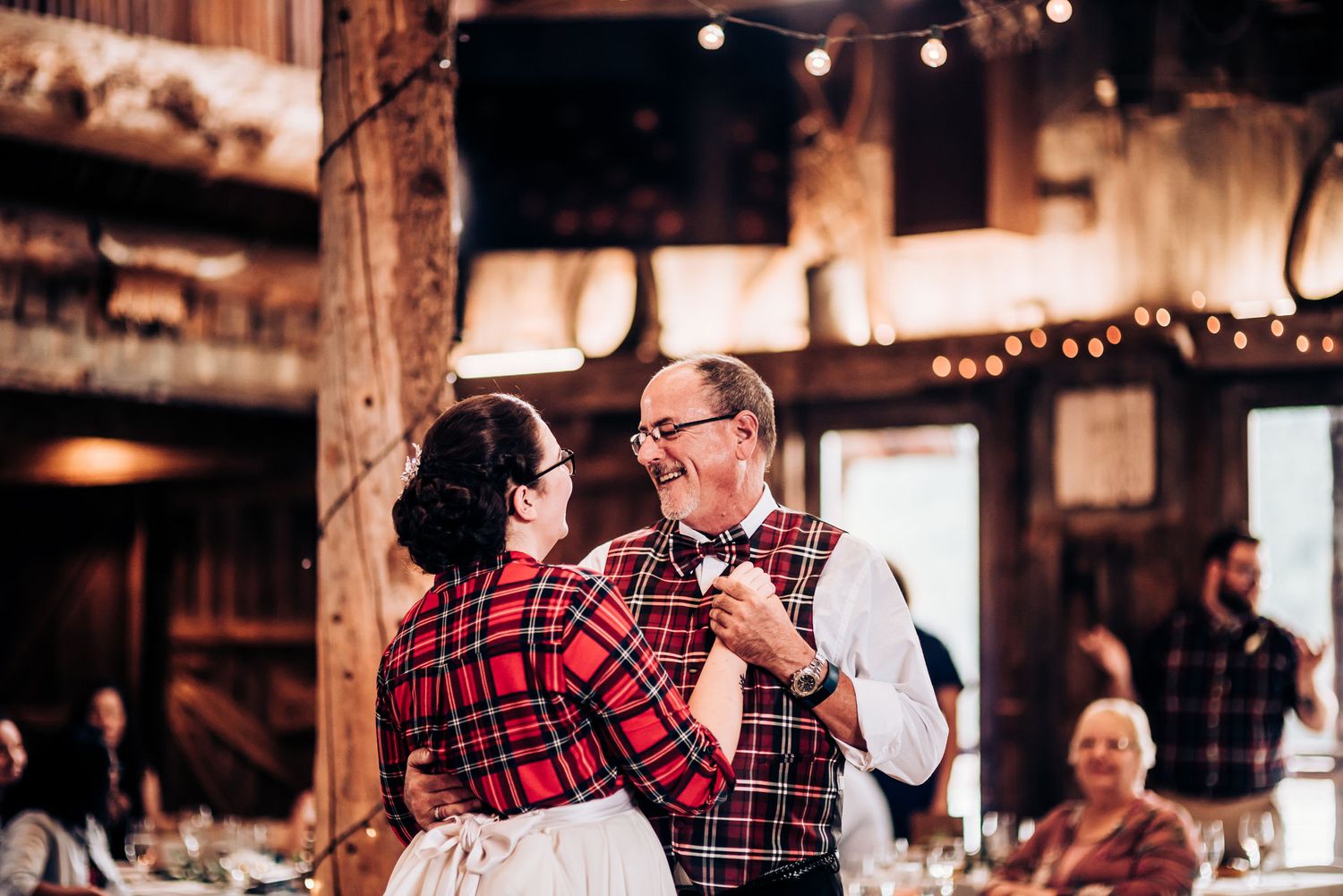 Couple dancing at rustic venue decorated with string lights.