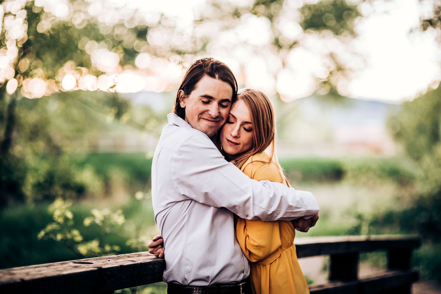 A couple embraces while wearing yellow dress and white shirt during a sunset photoshoot.