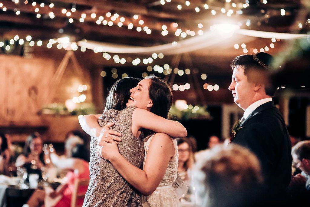 Emotional embrace shared during wedding celebration under warm fairy lights.