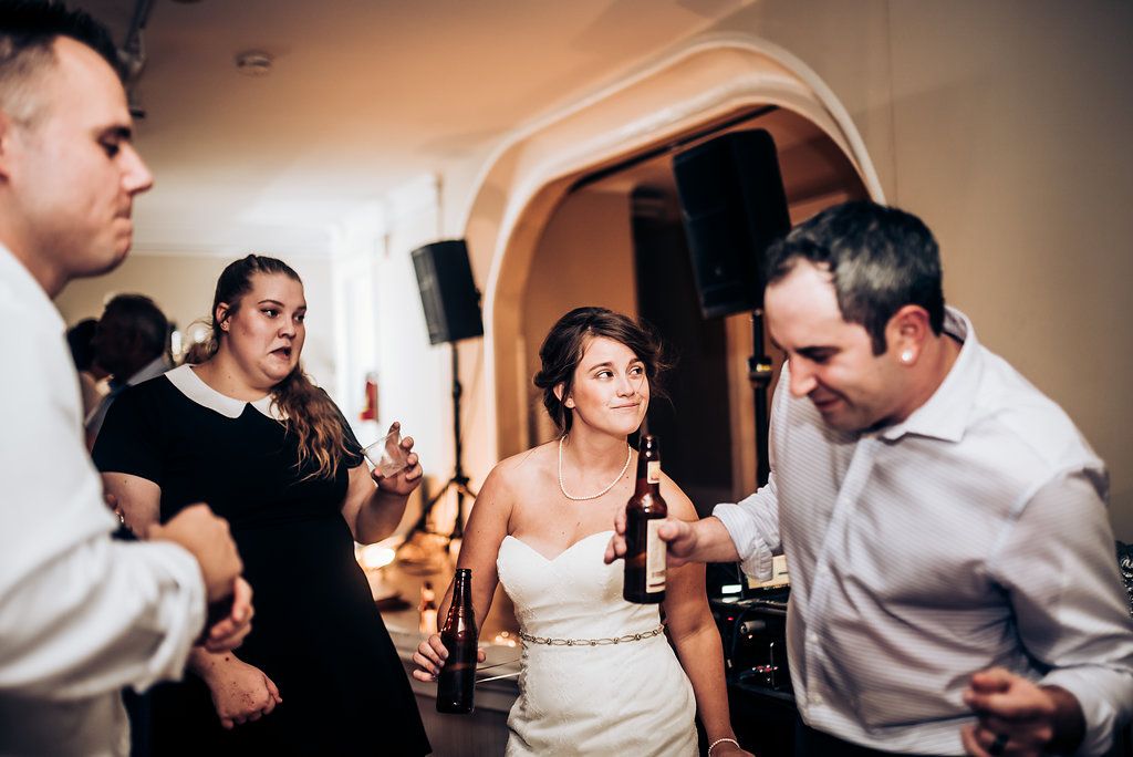 Guests enjoying drinks and dancing at a lively indoor wedding reception.