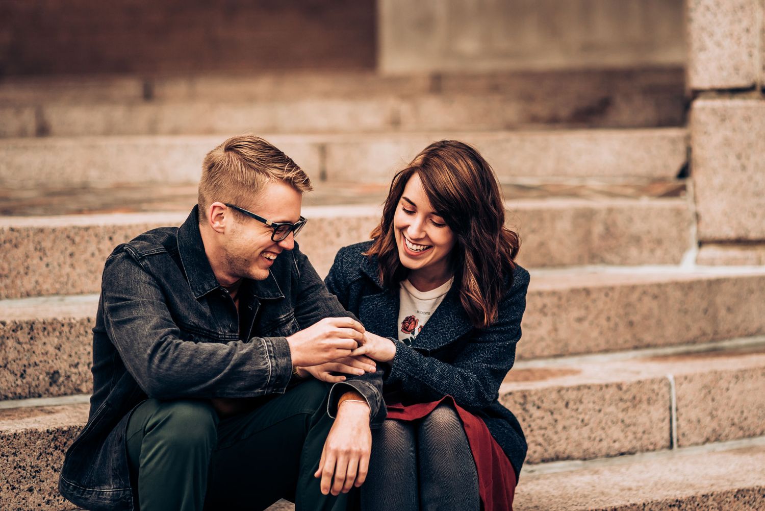 A couple looks at something together while sitting on stone steps.