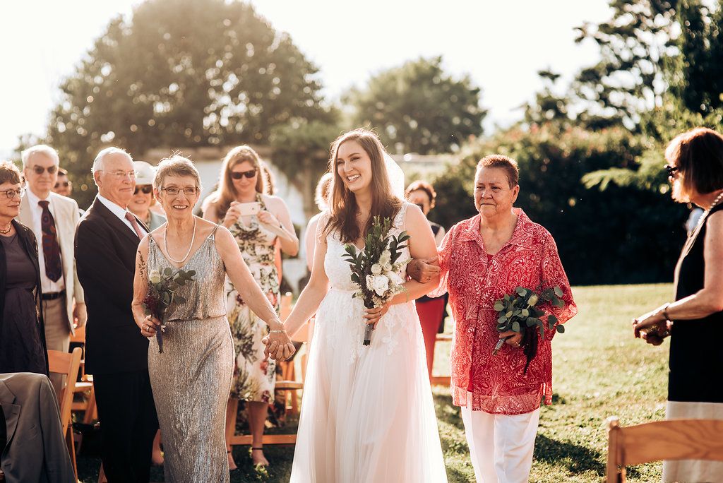 A wedding celebration takes place outdoors with guests in formal attire during sunset.