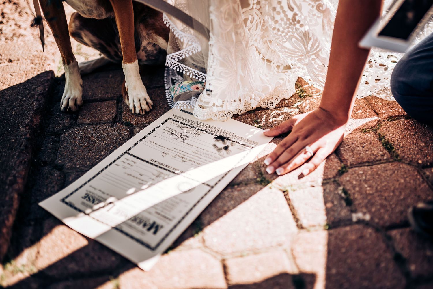 Wedding document being signed outdoors on textured brick surface.