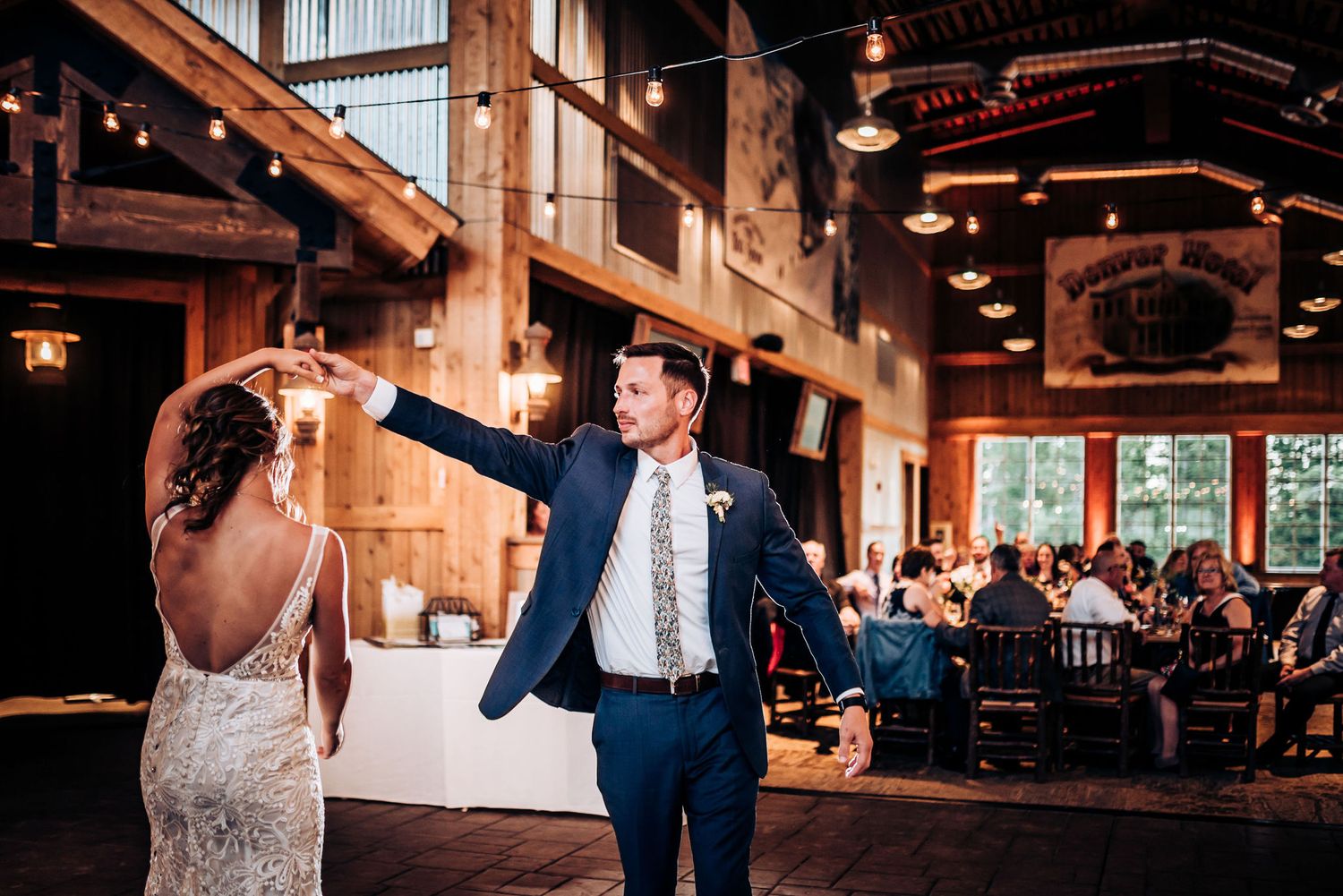 A couple performs a lively dance move during their wedding reception in a rustic venue.