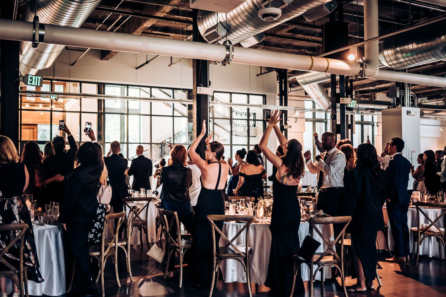 Stylish wedding reception venue with guests mingling and industrial-chic decor.