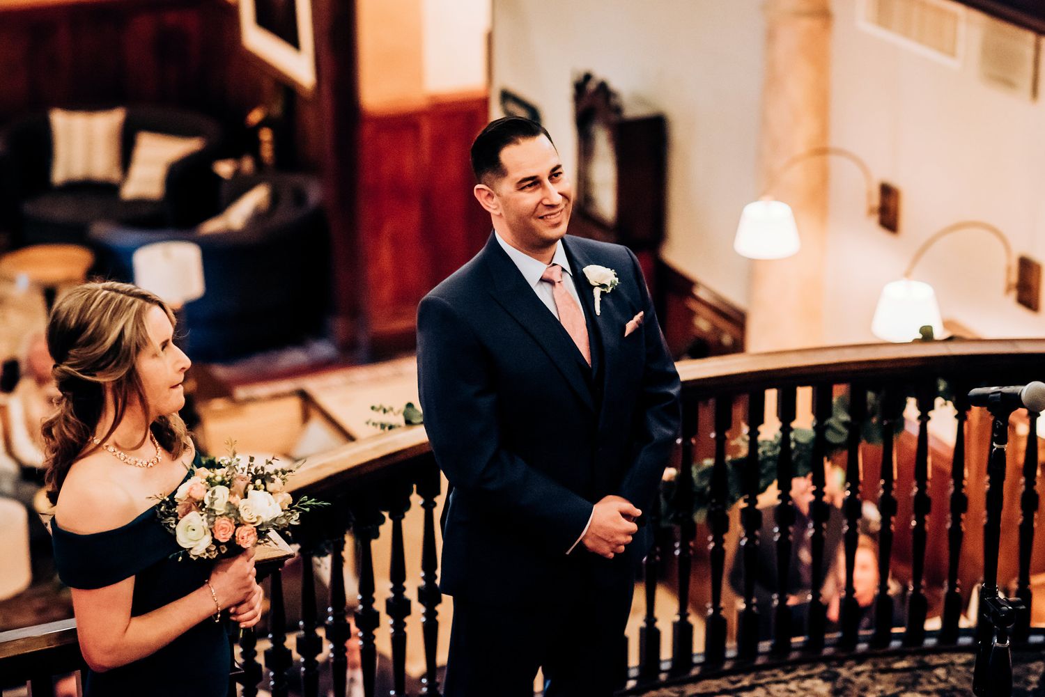 A formal occasion captured on an elegant wooden staircase with warm interior lighting.