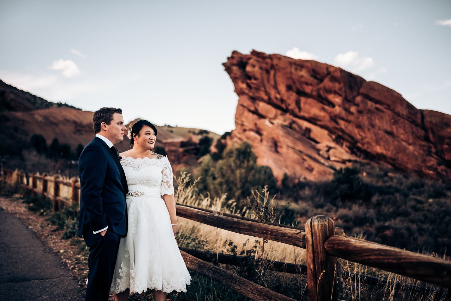 Wedding couple pose together at Red Rocks with dramatic rock formation in background.