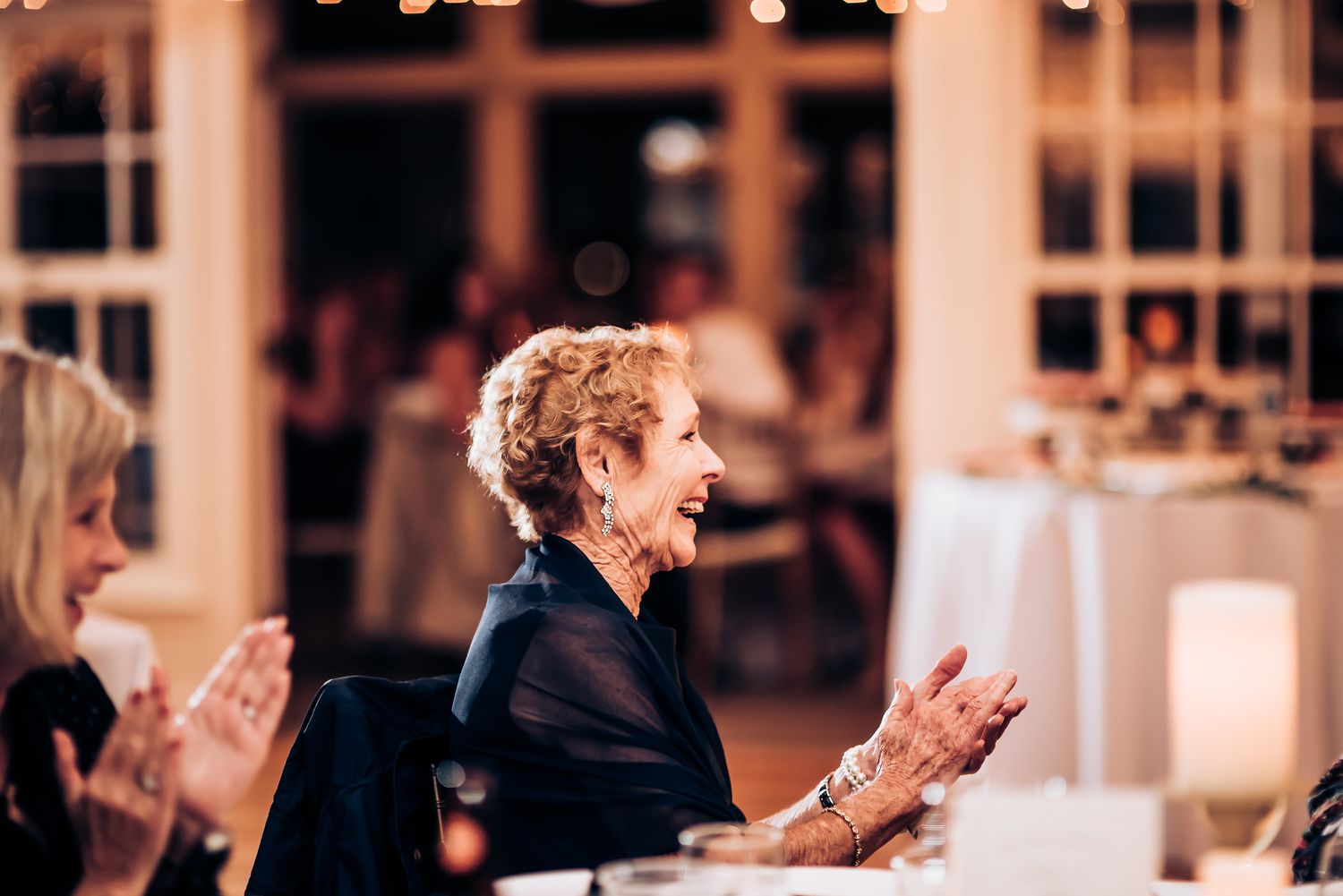 Guest clapping and smiling during a wedding reception celebration.