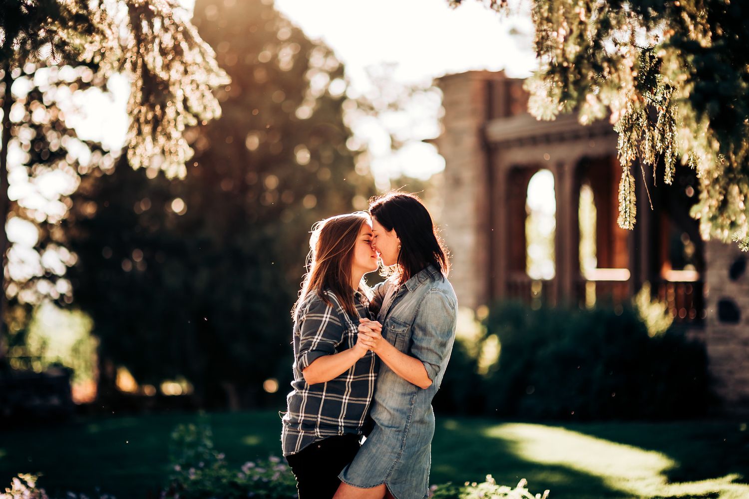 Two people share an intimate moment in front of historic stone architecture at sunset.