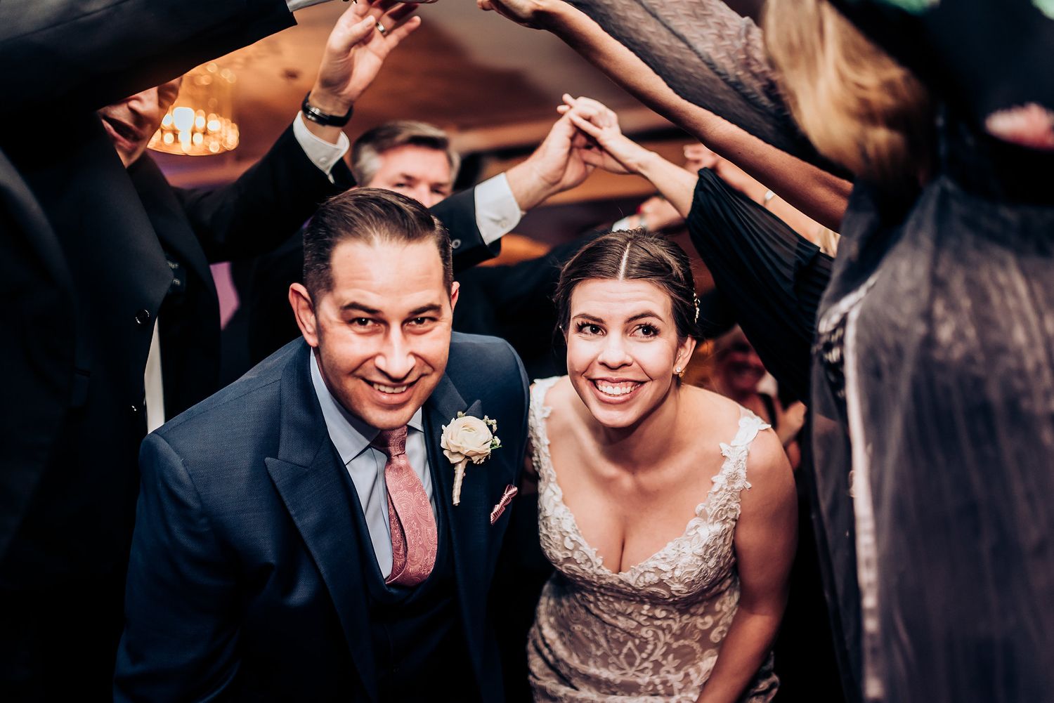 Joyful wedding celebration moment under archway of raised hands.
