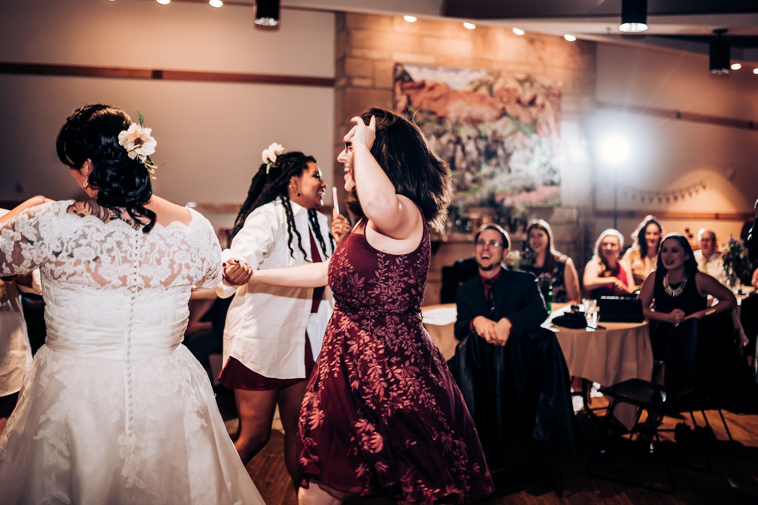 Wedding party members dance together during a lively reception celebration.