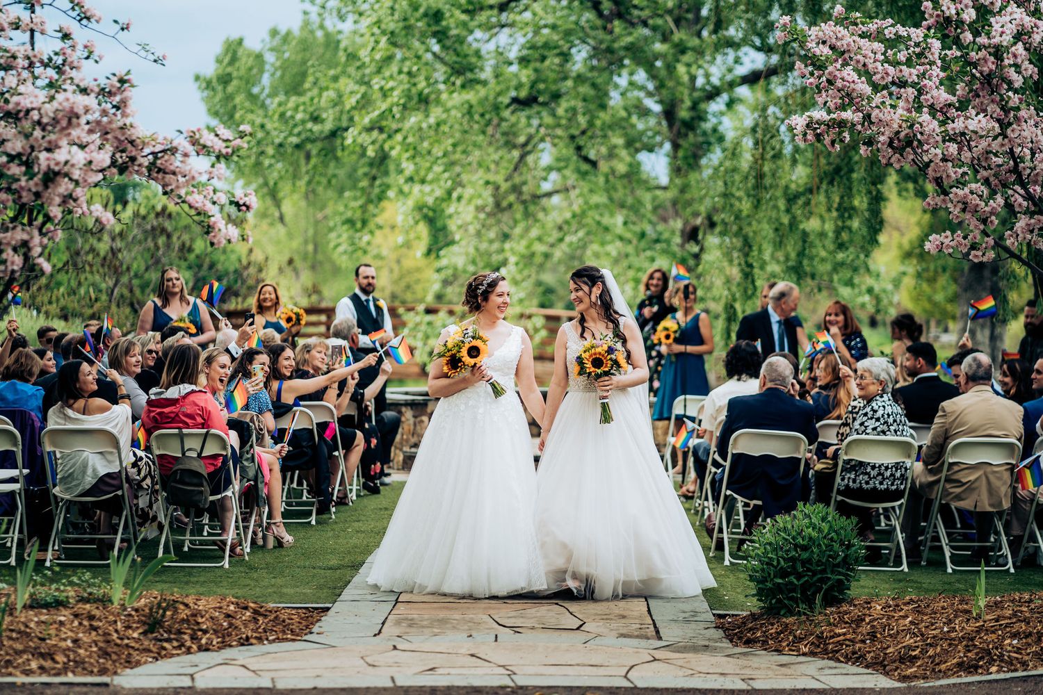 Outdoor wedding ceremony with white chairs and floral spring setting.