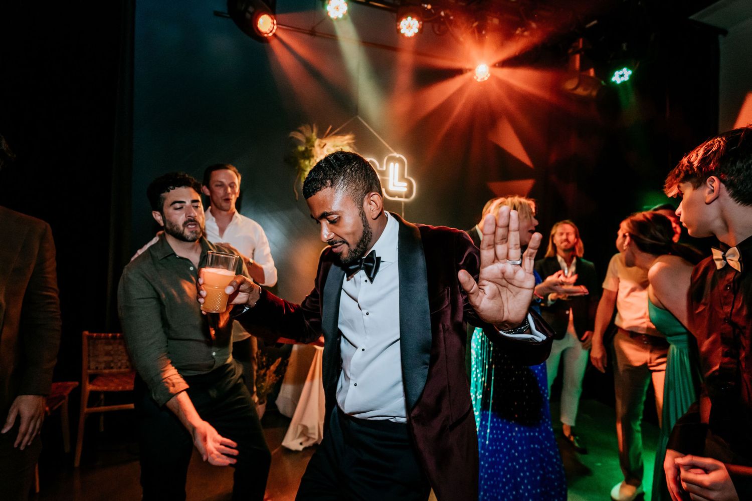 Guest dancing at nightclub venue with dramatic red stage lighting and crowd in background.