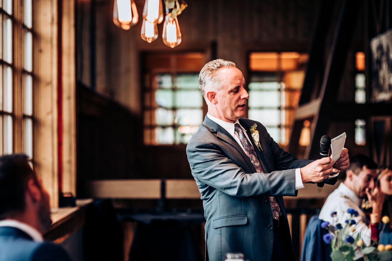 Someone gives a heartfelt speech at an evening reception while holding a microphone.