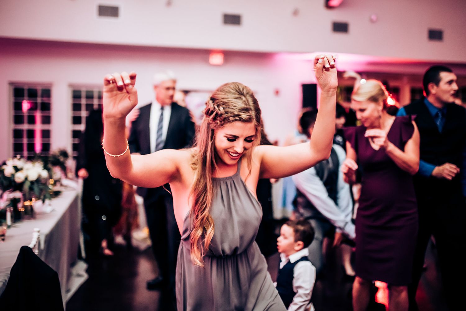 A guest dances enthusiastically with raised arms at a wedding reception.