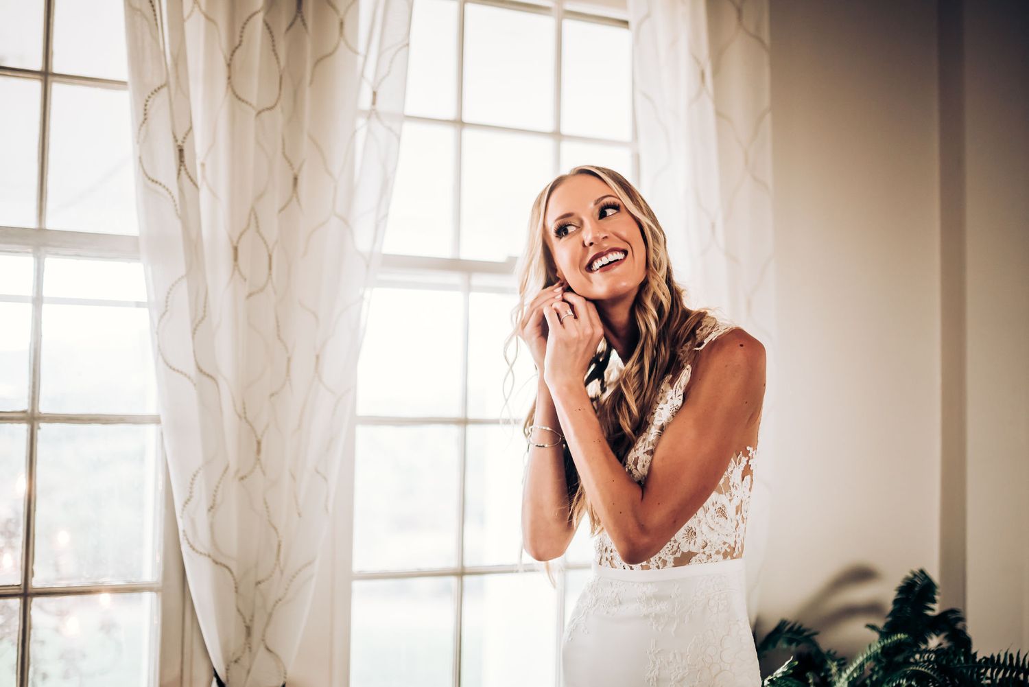 Joyful bridal moment captured by window light in an elegant room.