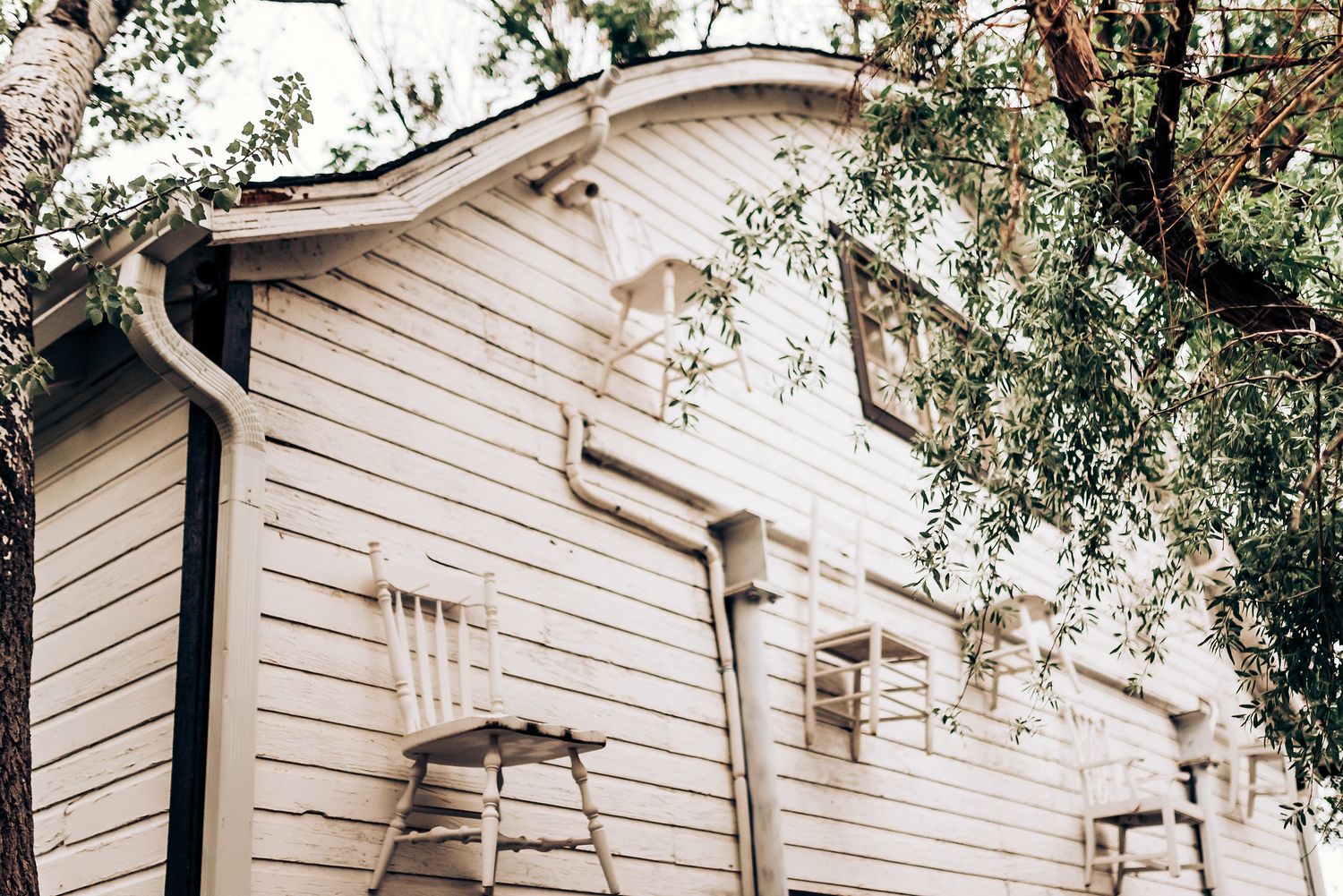White wooden exterior of a classic chapel with trees framing the architectural details.