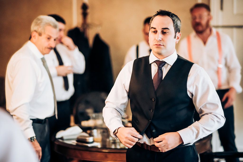 A man in a formal vest getting dressed for a special occasion.