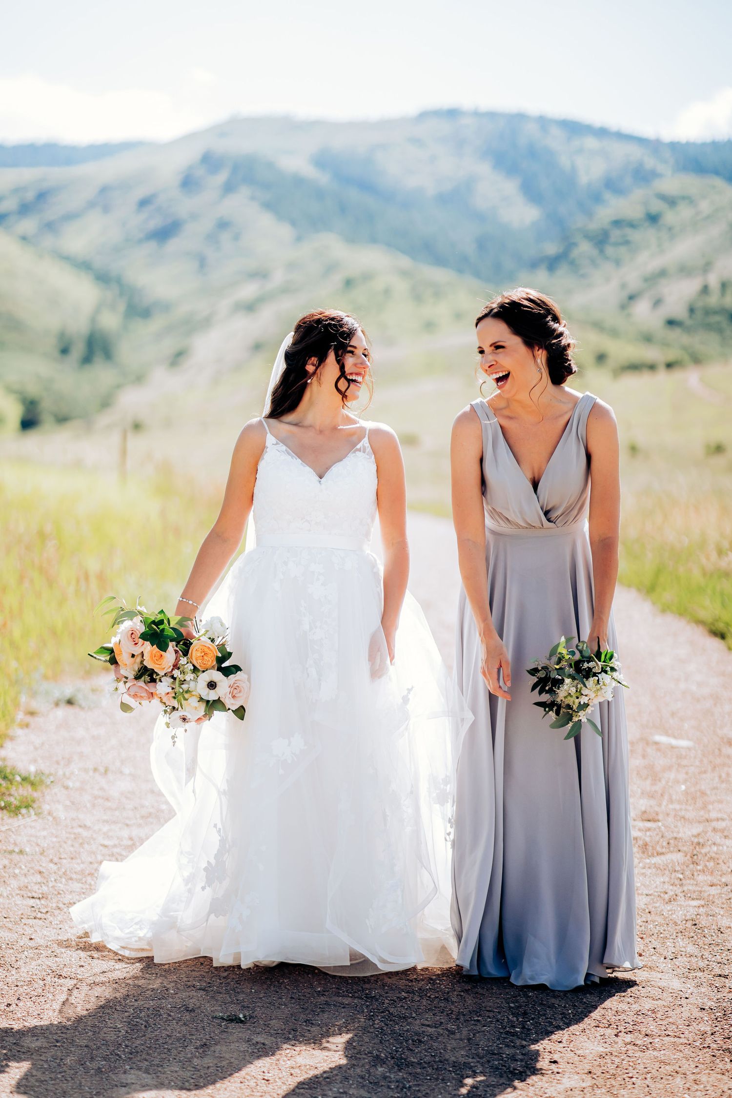 Two people in formal dresses walking together on mountain path.