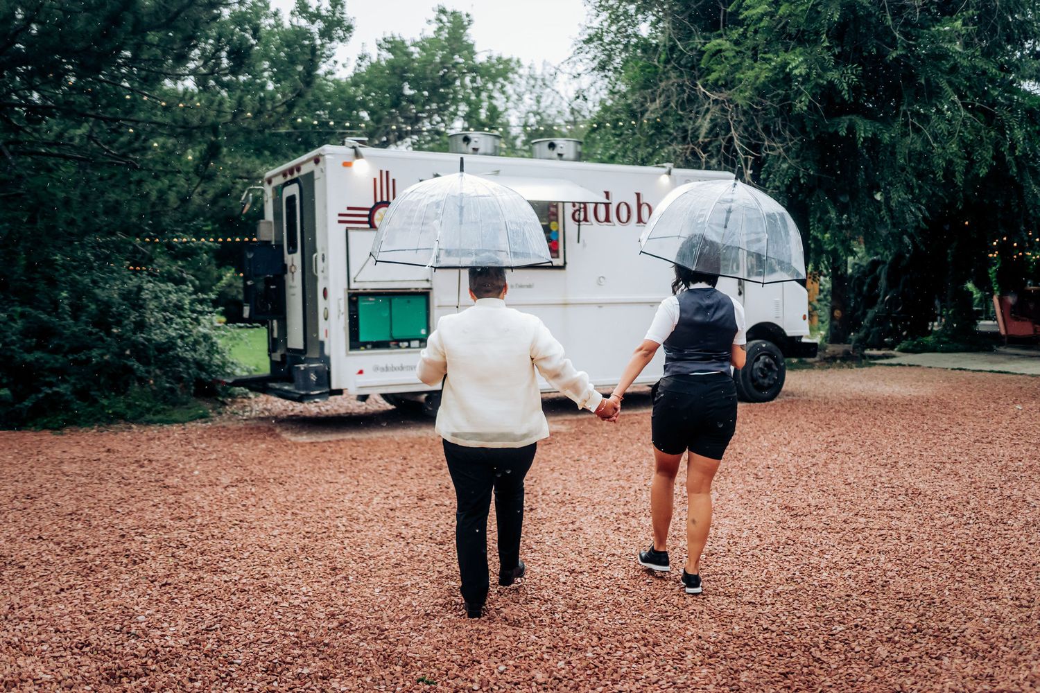Two people walking towards a vintage food truck on a gravel path.