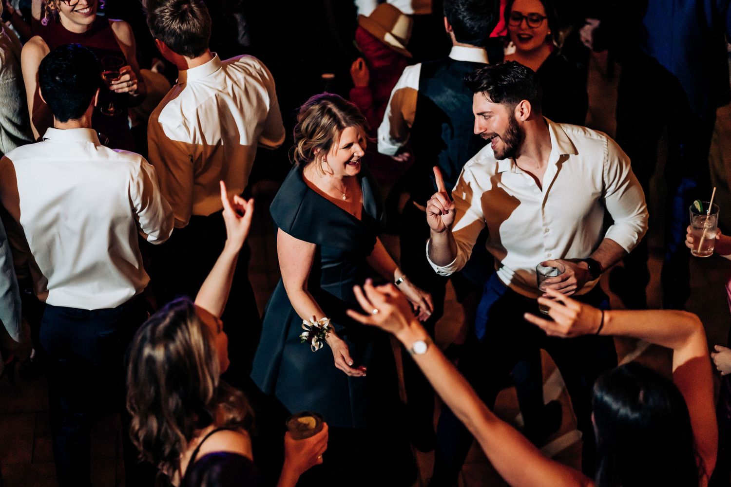 Party guests dancing and celebrating on a crowded dance floor.