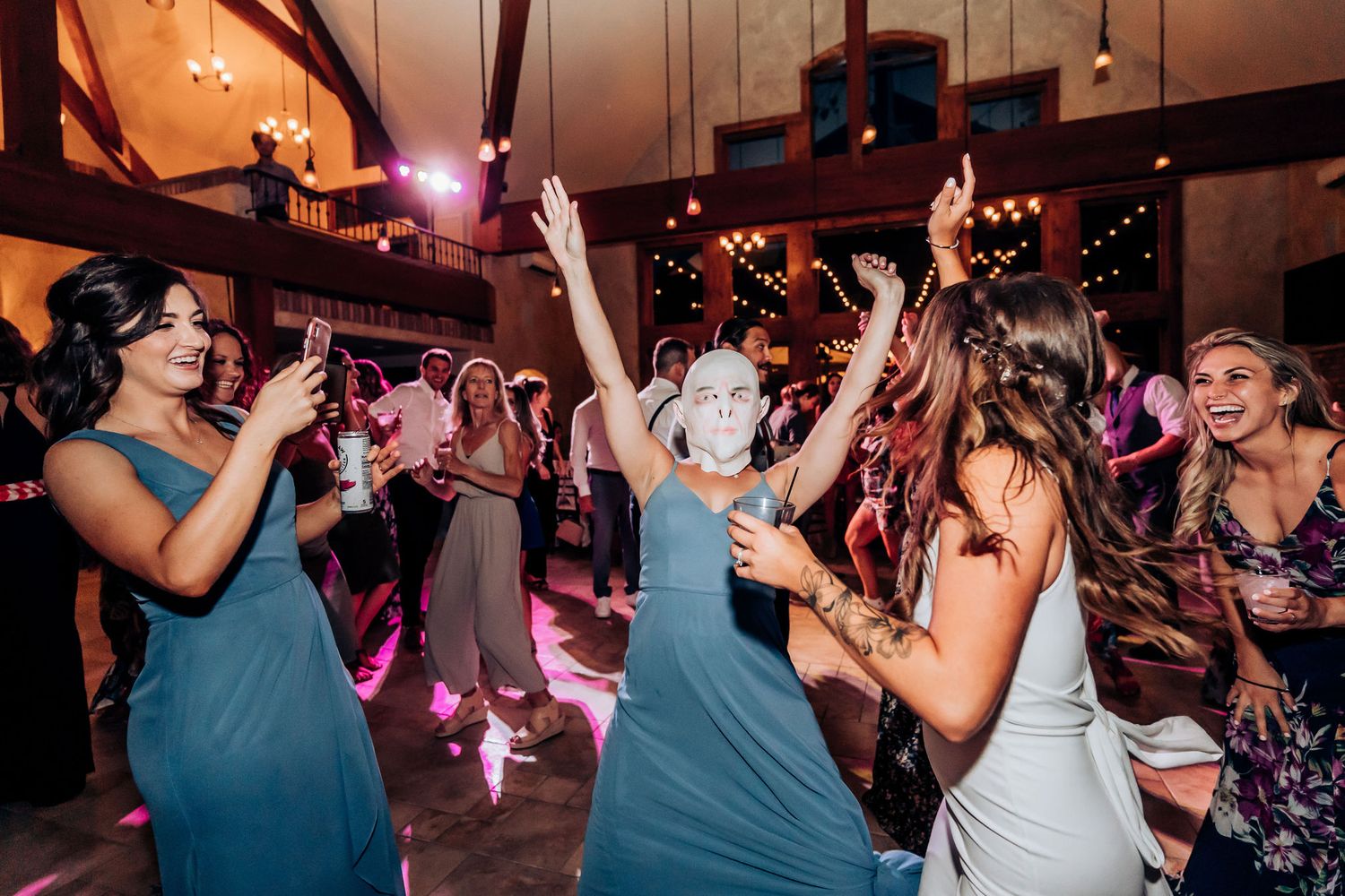 Wedding party guests in matching blue dresses dancing together on the dance floor.