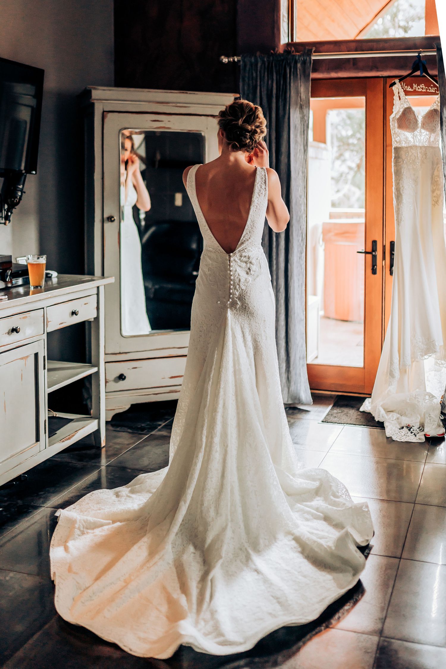 Elegant white wedding gown with open back and long train photographed against interior decor.
