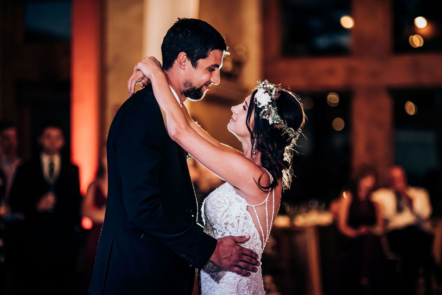 A couple shares an intimate dance moment at their wedding reception with soft lighting.