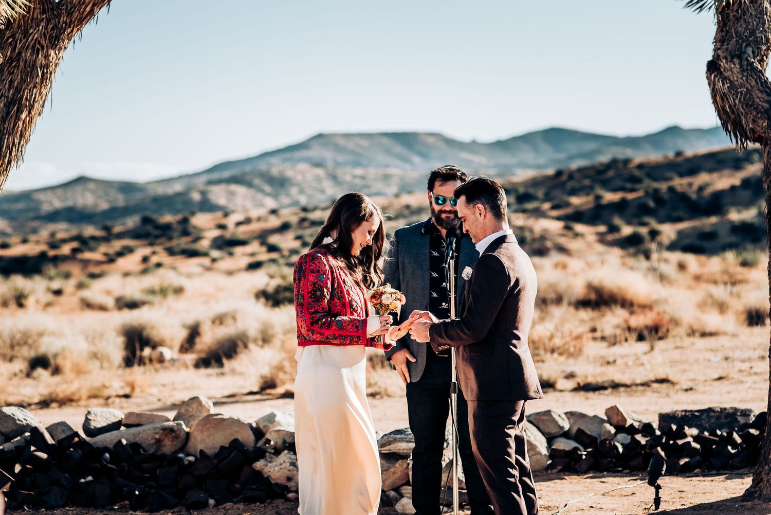 Desert wedding ceremony with mountains and Joshua trees creating a natural backdrop.