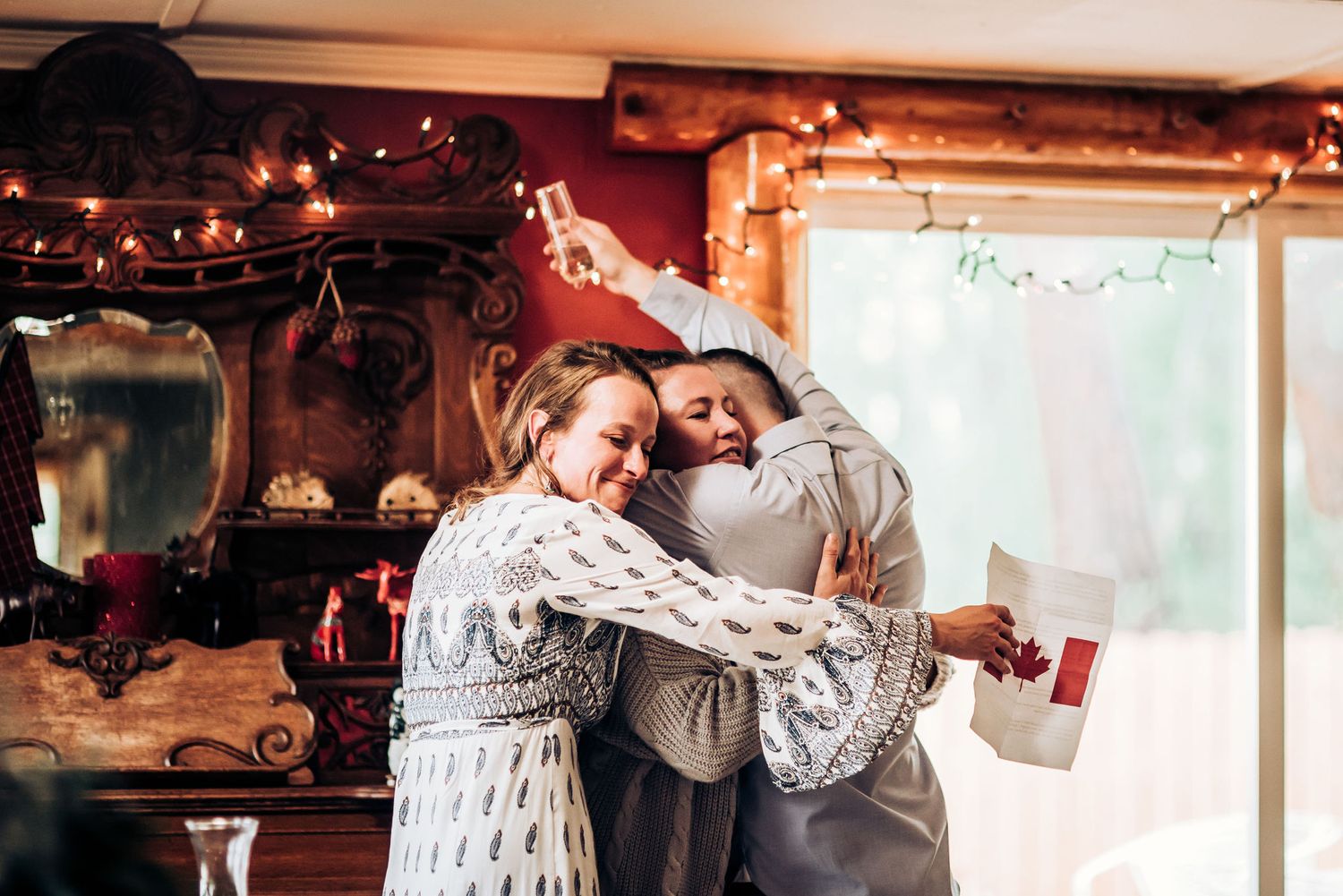 Celebrating with happy embraces during wedding reception under warm string lights.