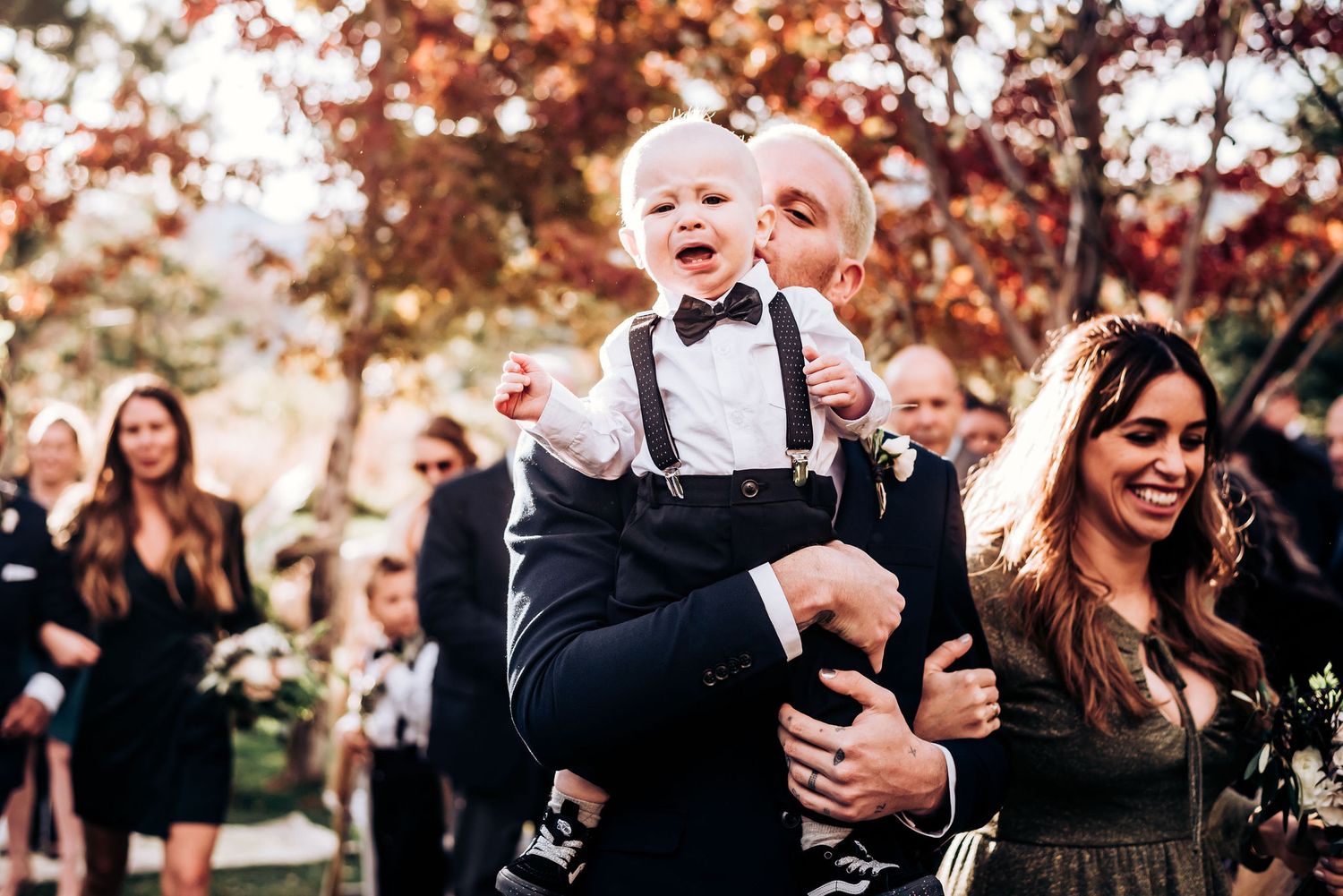 Joyful moment at outdoor wedding with guests in formal attire celebrating.