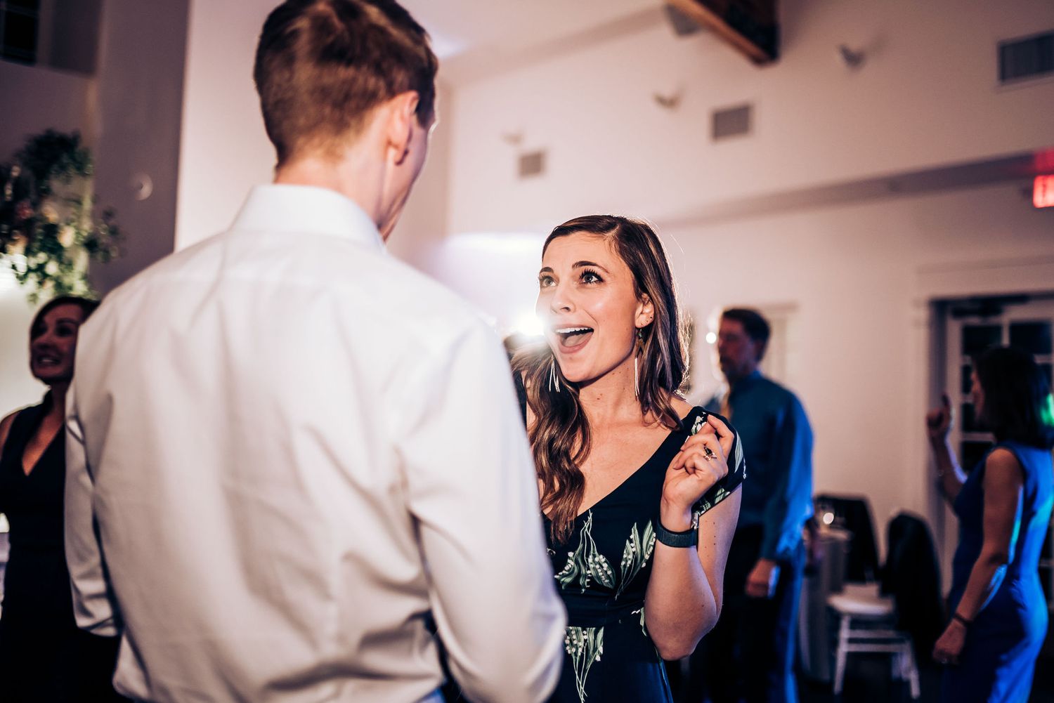 Guests share an energetic dance moment at wedding reception with ambient lighting.