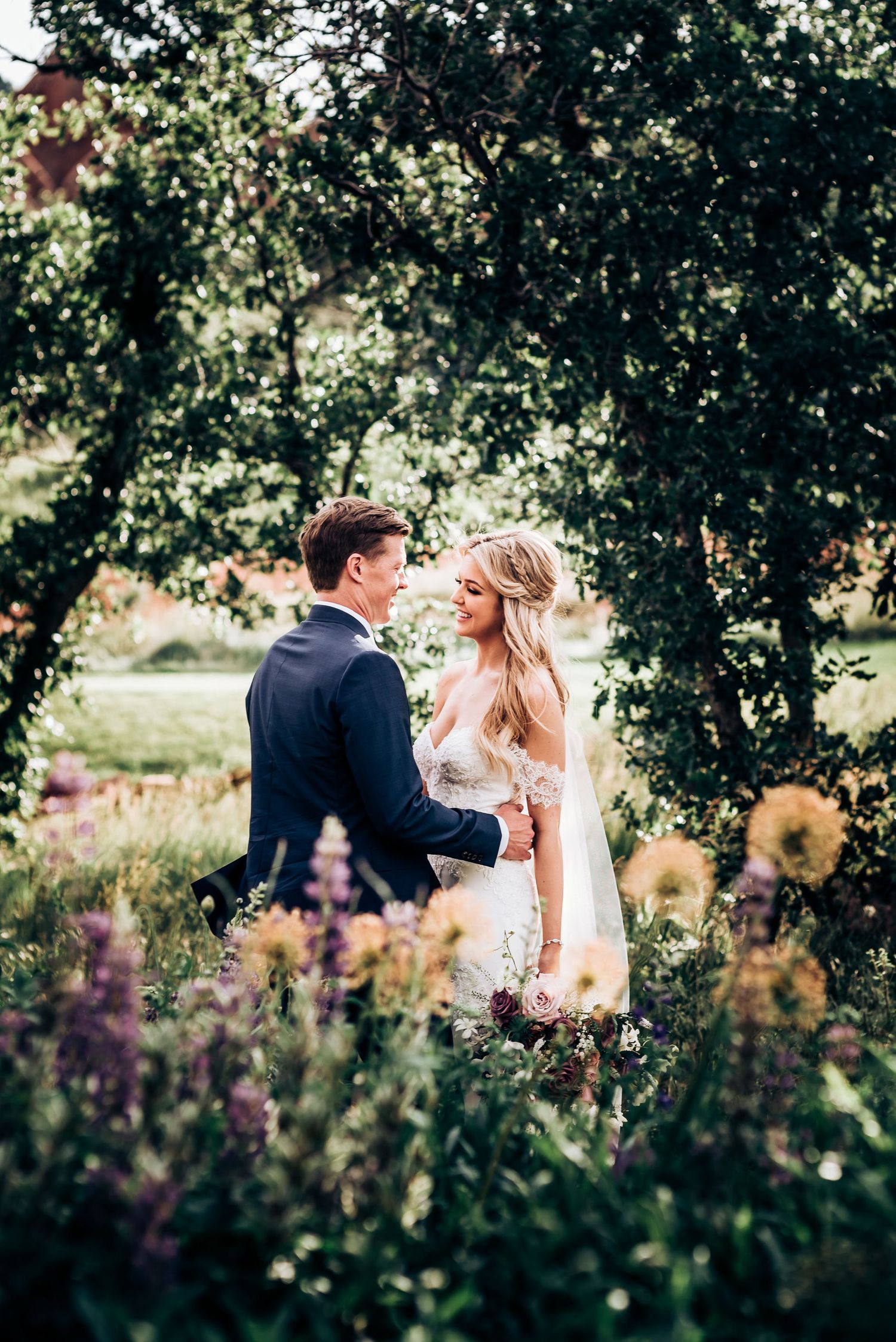 Romantic portrait of couple among blooming wildflowers and trees.