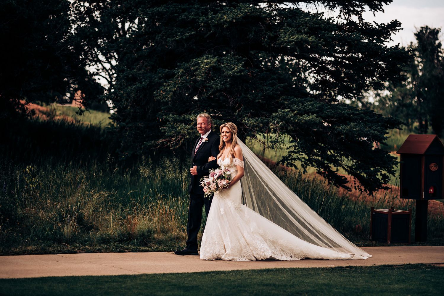 Wedding couple poses for photos on outdoor platform with scenic mountain views.
