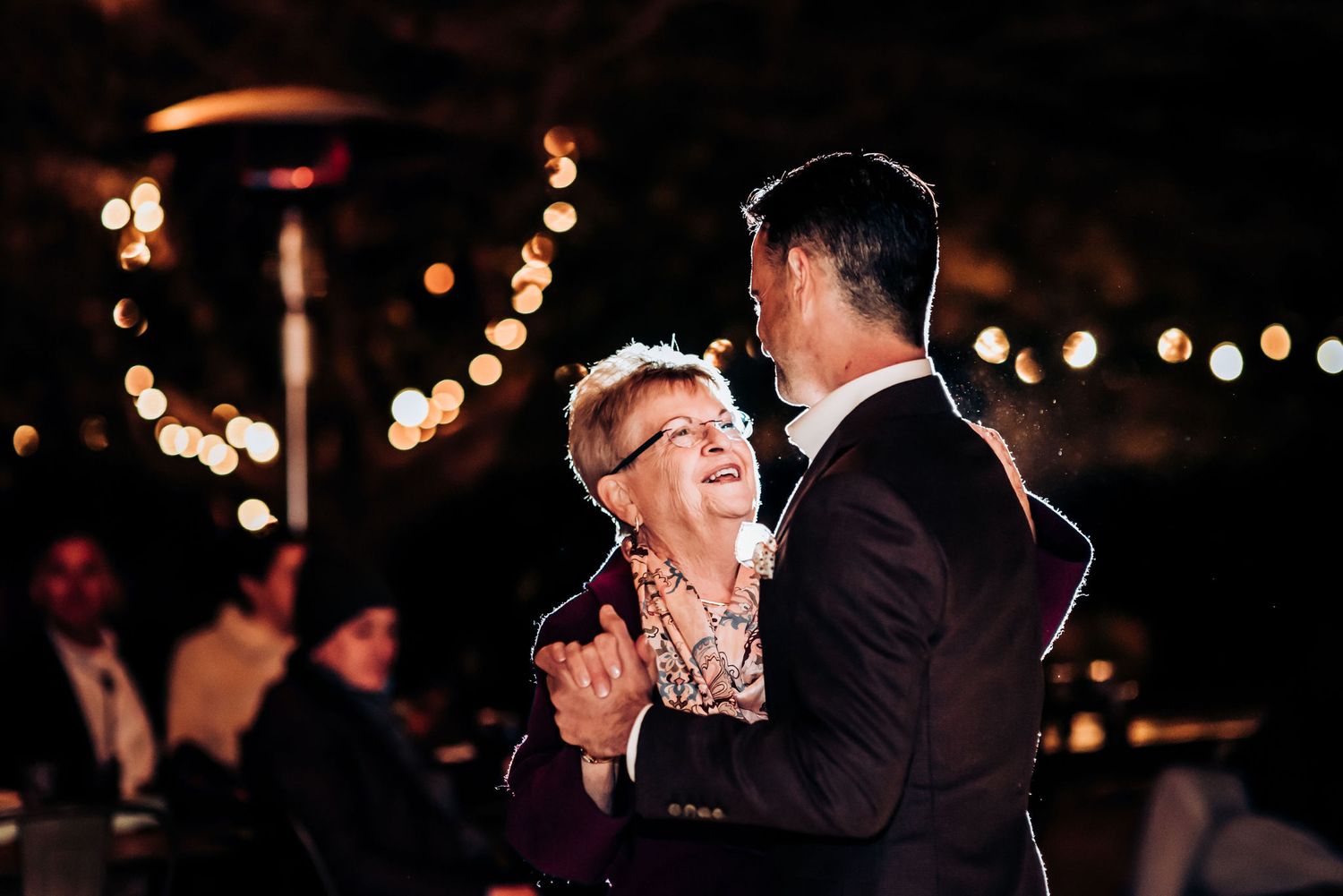 Dancing partners share joyful moment under warm outdoor party lights.