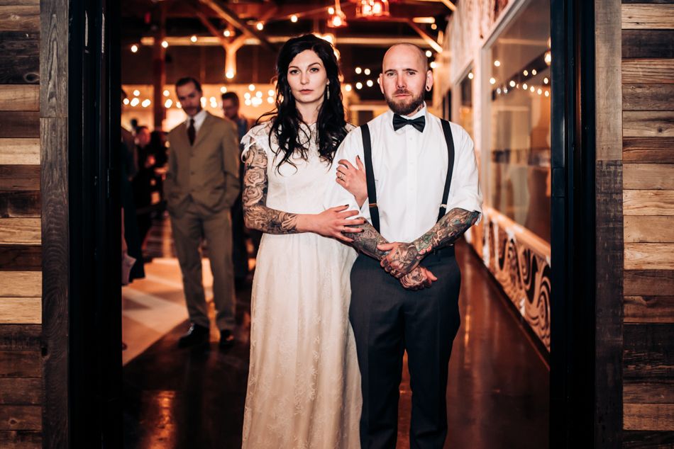 A wedding portrait in a rustic wooden hallway with illuminated signage.
