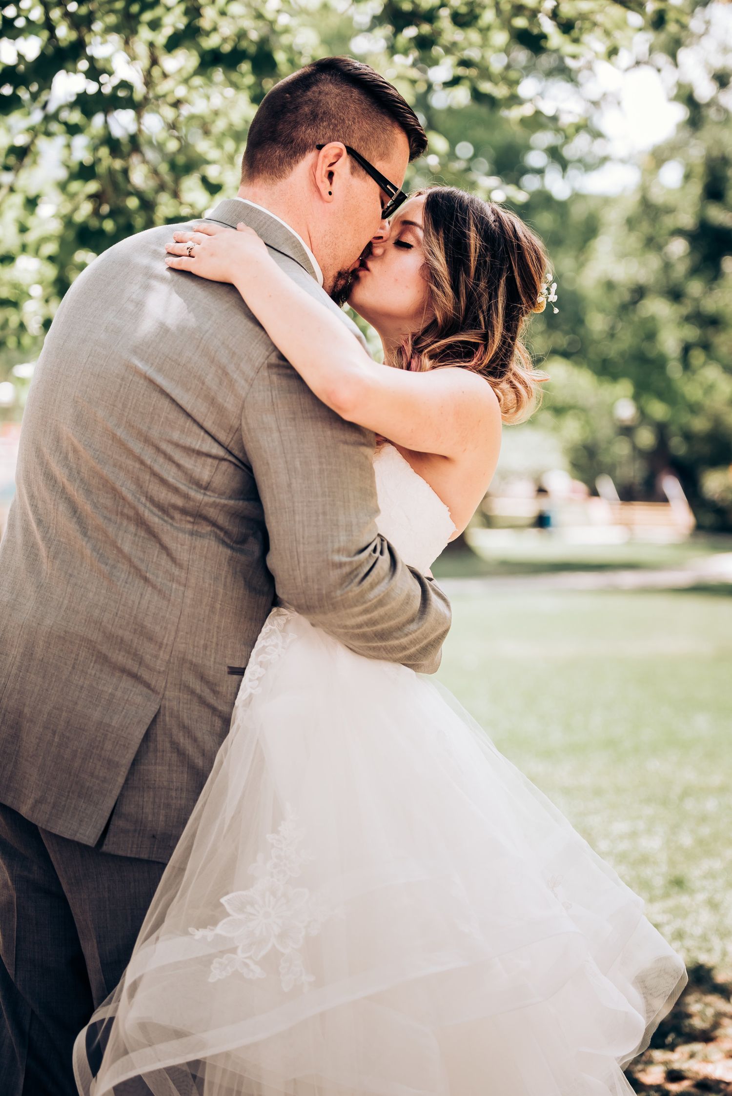 A romantic outdoor wedding moment captured in a sunlit park setting.