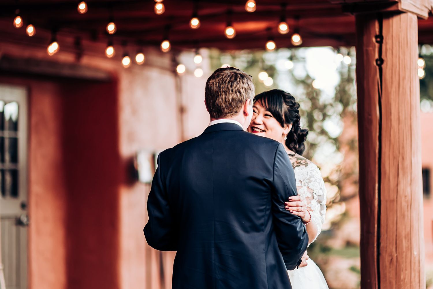 Intimate wedding moment captured on terrace with string lights and terra cotta walls.