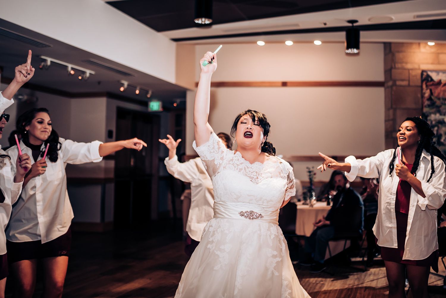Celebratory dance moment during a wedding reception with performers in white shirts.
