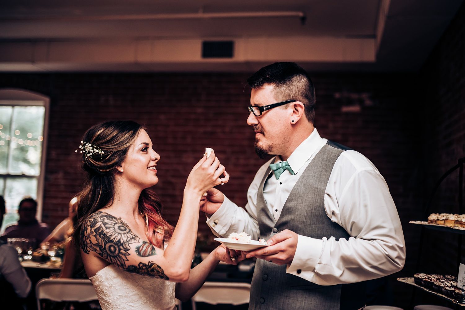 Couple sharing a playful moment while eating cake at their reception.
